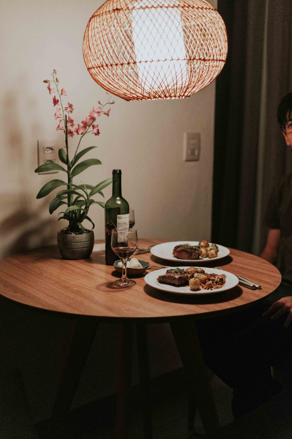 Elegant dining scene with wine, elegant food plates, and a blooming orchid on the side.