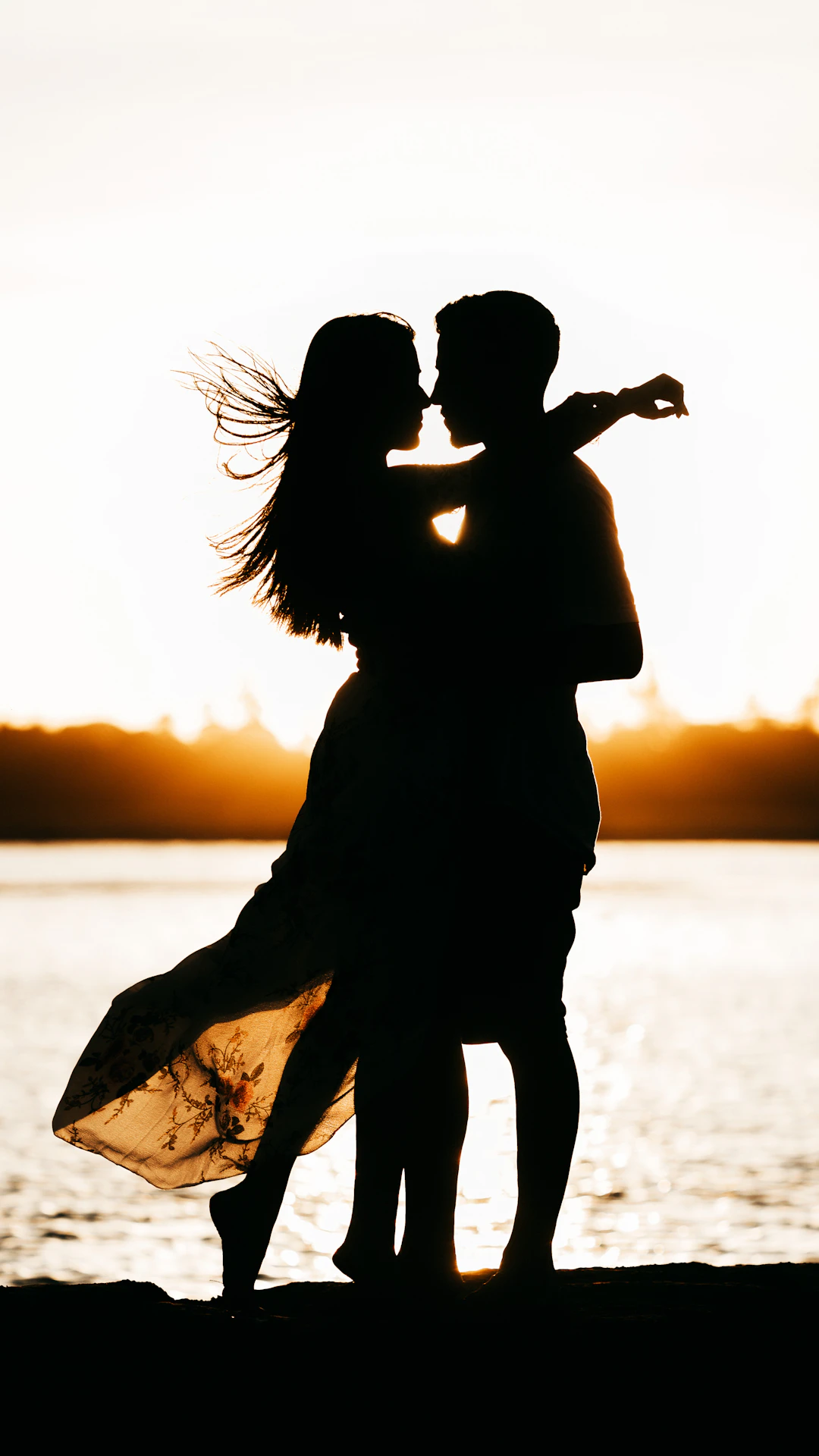 silhouette of woman standing on beach during sunset